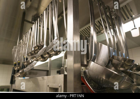 Viele Kochtöpfe und Pfannen hängen von einem Rack in einem Restaurant Küche hautnah und im Detail Stockfoto