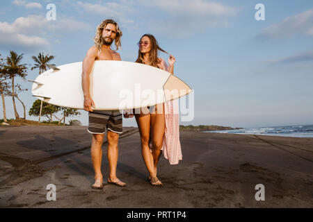 Paar stehend mit Surfbrett am Strand in Bali, Indonesien Stockfoto