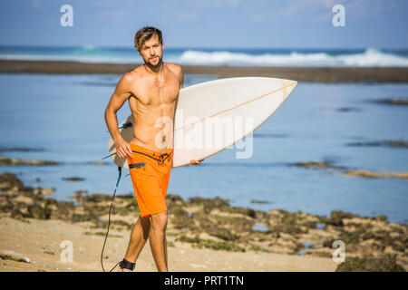 Surfer mit Surfen Board läuft auf Sandstrand auf Sommer Tag Stockfoto