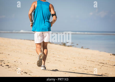 Rückansicht der runner Ausbildung auf Sand Strand in der Nähe von Meer, Bali, Indonesien Stockfoto