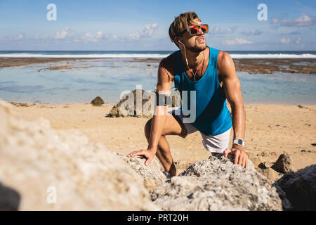 Sportler, die beim Klettern auf den Felsen am Strand, Bali, Indonesien Stockfoto