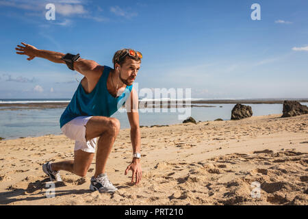 Athletischer Mann mit Armband tun stürzt während des Trainings am Meer Stockfoto