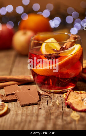 Nahaufnahme Blick auf lecker Glühwein trinken, Schokolade und Gewürzen auf Holz- Oberfläche mit bokeh Lichter auf Hintergrund Stockfoto
