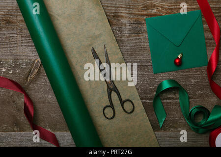 Flach mit leeren Umschlag, Schere, Papier und Bänder für Weihnachtsgeschenke auf hölzernen Tischplatte Stockfoto