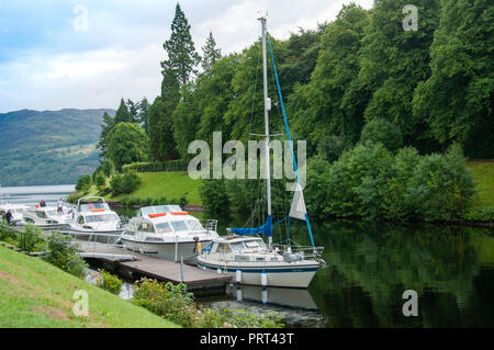 Yachten und Boote auf einem ruhigen Einlass unten Ersten Augustus mit dem Loch Ness Gewässer im Hintergrund die Stille des Tages wider. Stockfoto