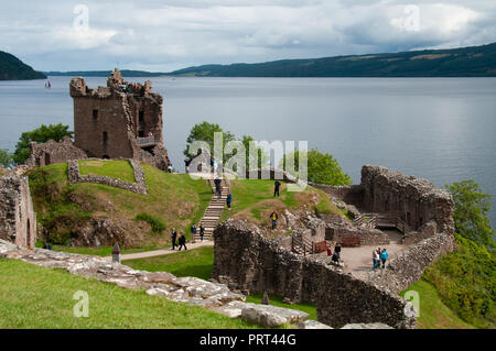 Touristen, die in der historischen Ruinen von Urquhart Castle mit Blick auf Loch Ness, Schottland Stockfoto