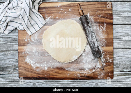 Hausgemachte butter Pie Crust Teig mit Rolling Pin und Handtuch über Bemehlten rustikalen Holzmöbeln Hintergrund. Bild geschossen von Overhead. Stockfoto