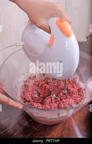 Happy Boy mischen ingradients in die Glasschale und Vorbereitung einer Red Velvet Cake. Stockfoto
