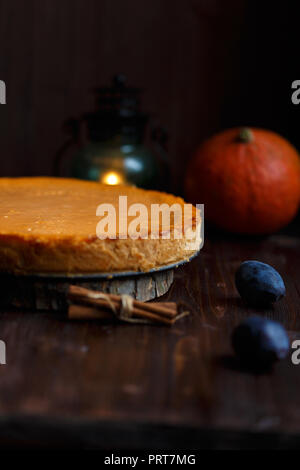 Pumpkin Cheesecake, zu Hause, Kürbis, Pflaumen gekocht, Vanille auf Holz dunkel Tabelle. Herbst und Winter gemütliche Konzept. Menü und Restaurant Konzept in der Nähe u Stockfoto
