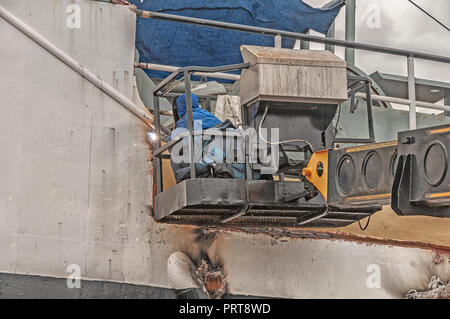 Schweißer bei der Arbeit auf einem Schiff sitzen in einem Käfig von einem Kran Schweißen eine Stahlplatte Stockfoto