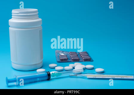 Weiße pillen Neben der Flasche und Löffel auf blauem Hintergrund in der Nähe der Spritze. Medical Center im Krankenhaus. Stockfoto