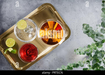 Drei alkoholische Cocktails in einer Brille auf einem goldenen Tablett das Konzept einer Partei und an den Feiertagen. Ansicht von oben. Stockfoto