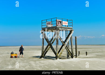 Mann mit Handkarren auf eine Rettung Turm auf einer Untiefe im Wattenmeer bei Ebbe an der Nordsee, Leuchtturm Westerhever Schleswig-Holstein, Deutschland Stockfoto