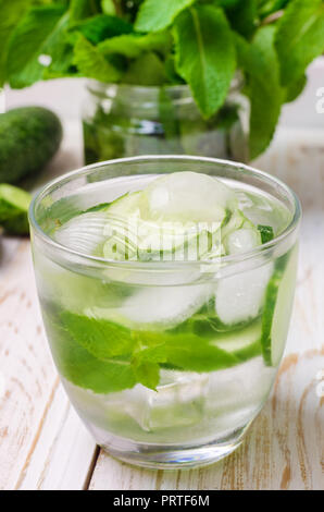 Frisches Wasser mit Gurke, Minze und Eis im Glas in Holz- fach, Nahaufnahme. Stockfoto