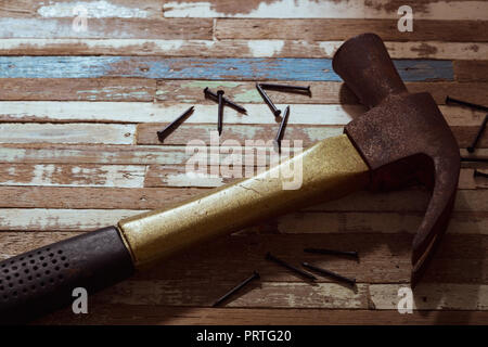 Rostige Hammer mit Nägeln auf einem grunge Holz Hintergrund. Stockfoto