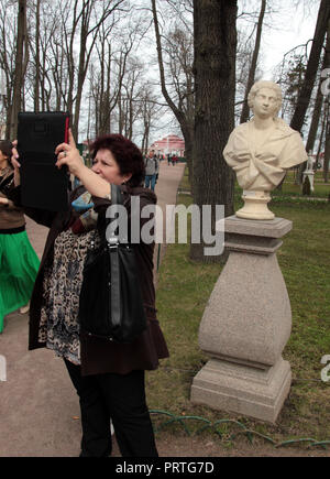 Eine Frau nimmt ein Foto von sich selbst, mit einer Statue, auf Ihrem Laptop Computer in St. Petersburg, Russland. Stockfoto