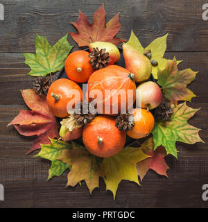 Herbst noch Leben mit bunten Blättern, Reife orange Kürbisse, Äpfel auf Holzbrett. Kopieren Sie Platz. Blick von oben. Stockfoto
