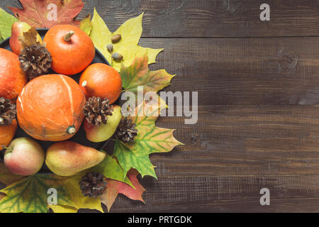 Herbst noch Leben mit bunten Blättern, Reife orange Kürbisse, Äpfel auf Holzbrett. Kopieren Sie Platz. Blick von oben. Stockfoto