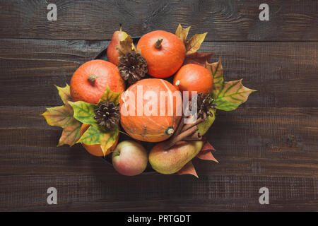Herbst noch Leben mit bunten Blättern, Reife orange Kürbisse, Äpfel auf Holzbrett. Kopieren Sie Platz. Blick von oben. Stockfoto