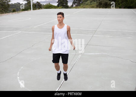 Männliche Teenager basketball Player auf Basketballplatz überspringen Stockfoto