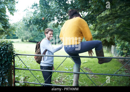 Wanderer paar Klettern über Farm gate Stockfoto