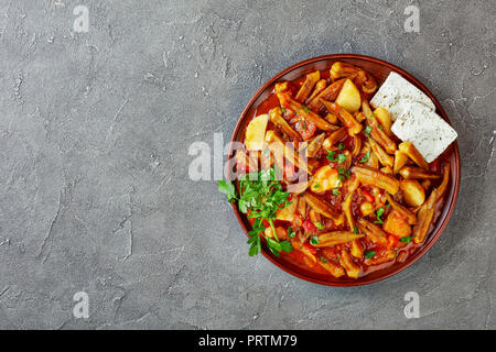 Okra Mpamies Giaxni mit Tomaten und Kartoffeln, mit Feta Käse auf einem Ton Platte auf grauem Beton Tisch serviert, griechisch Rezept, fr Stockfoto