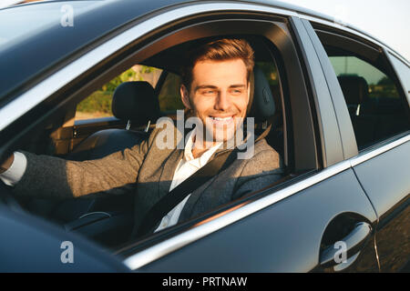 Vorderansicht des lächelnden bussinesman in seinem Auto fährt Stockfoto