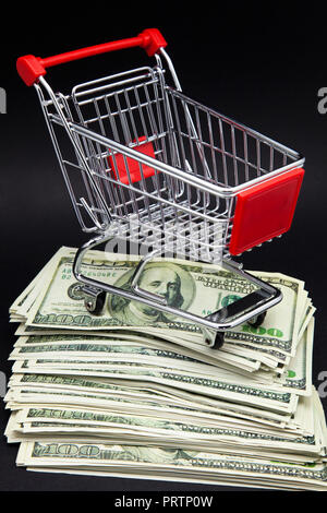Warenkorb auf einem Stapel von Banknoten von einhundert Dollar Stockfoto