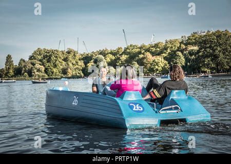 Freunde paddeln auf einem Tretboot auf dem Serpentine-See im Londoner Hyde Park, London, UK Stockfoto