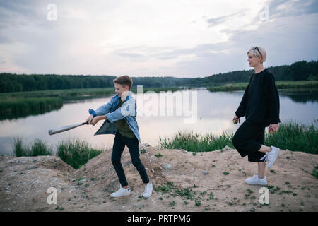 Glückliche Mutter und Sohn spielen mit Baseballschläger in der Nähe des Sees Stockfoto