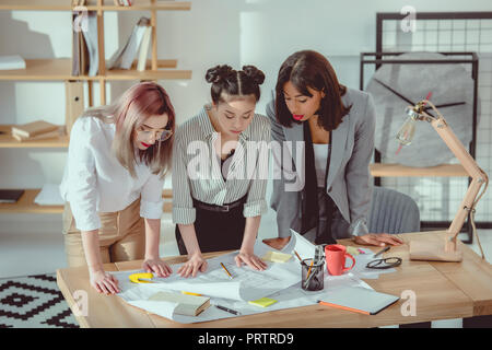 Jungen multiethnischen Designer auf der Suche nach Baupläne im Amt stehende Stockfoto