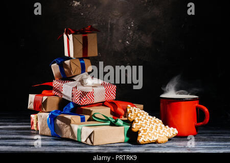 Nahaufnahme der Tasse mit heißem Getränk, Lebkuchen Cookie und Weihnachten Geschenke Stockfoto