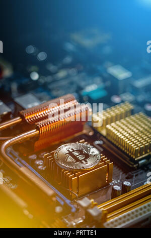 Die goldmünze der digitalen crypto Währung Bitcoin liegt auf der Hauptplatine des Computers Stockfoto