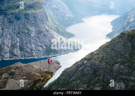 Tourist mit norwegischer Flagge. Ringedalsvatnet See. Blick von der Klippe in der Nähe der Trolltunga. Touristische Attraktion von Norwegen Stockfoto