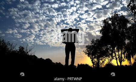 Girl Silhouette gegen den blauen Himmel mit Cirrus Wolken bei Sonnenuntergang Stockfoto