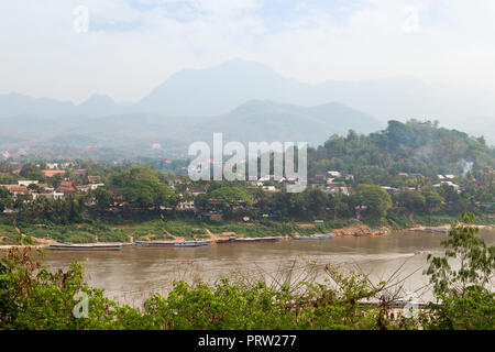 Angelegte Boote auf dem Mekong Fluss, Stadt Luang Prabang, Mount Phousi (Phou Si, Phusi, Phu Si) und Berge im Hintergrund in Luang Prabang, Laos. Stockfoto