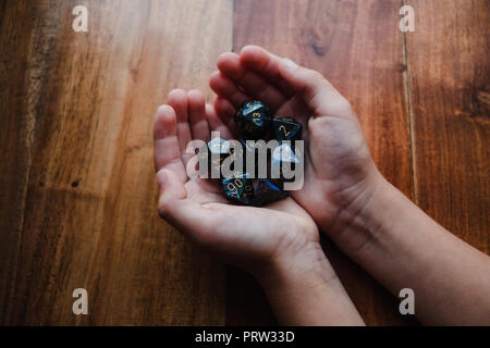 Mädchen mit hohlen Händen am Tisch holding Rolle zu würfeln, Nahaufnahme Stockfoto