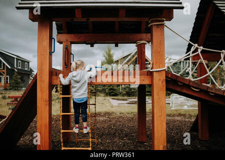 Mädchen klettern Leiter zum Spielplatz Plattform, Rückansicht Stockfoto