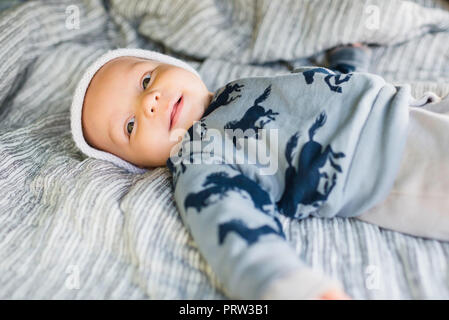 Smiling baby boy liegend auf Bett Stockfoto