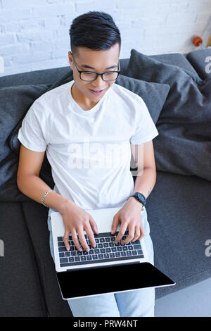 Hohe Betrachtungswinkel von Stattlichen asiatische mit Laptop auf dem Sofa zu Hause Mann Stockfoto
