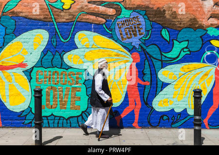 England, London, Shoreditch, Brick Lane, älteren muslimischen Mann Street Art vorbei gehen. Stockfoto