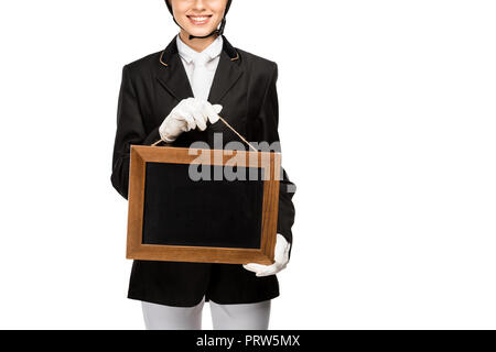 7/8 Schuß von lächelnden jungen Reiterin in Uniform Holding leere Schiefertafel isoliert auf weißem Stockfoto