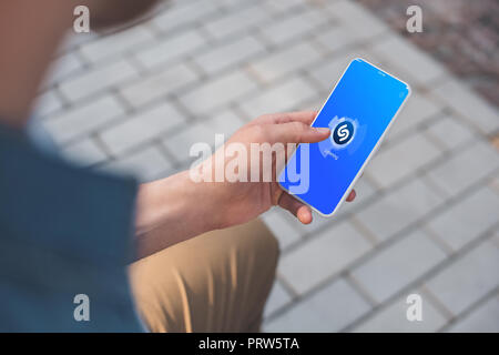 7/8-schuss mit Smartphone mit Shazam auf dem Bildschirm Mann Stockfoto