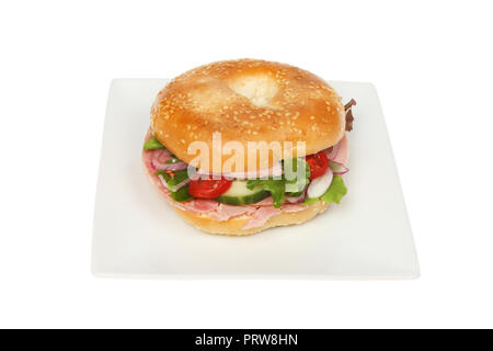 Schinken und Salat in einem Gesäte Bagel auf einer Platte gegen Weiße isoliert Stockfoto