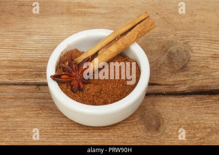 Chinesischen fünf Spice in einem ramekin mit einer Zimtstange und Sternanis auf alten verwittertes Holz Stockfoto