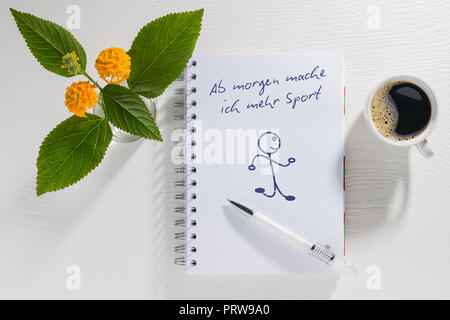 Schreibblock mit Auflösung des neuen Jahres mit Kaffeetasse und Blumen auf einem weißen Tisch Stockfoto