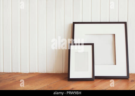 Zwei Poster auf dem Holzboden durch die weisse Wand mit Kopie Raum Stockfoto