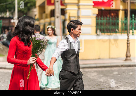 Ho Chi Minh City, Vietman - 21. Oktober 2016. Junges Paar in formelle Kleidung, Hände halten in der Notre Dame Platz in Ho Chi Minh City gekleidet. Roma Stockfoto
