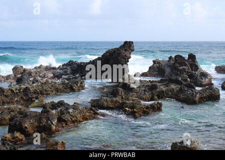 Kleine Wellen auf einem vulkanischen Felsen outcroppings am Hookipa Beach, Maui, am Anfang der Straße nach Hana Stockfoto