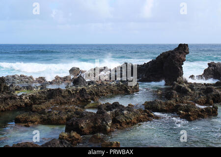 Kleine Wellen auf einem vulkanischen Felsen outcroppings am Hookipa Beach, Maui, am Anfang der Straße nach Hana Stockfoto